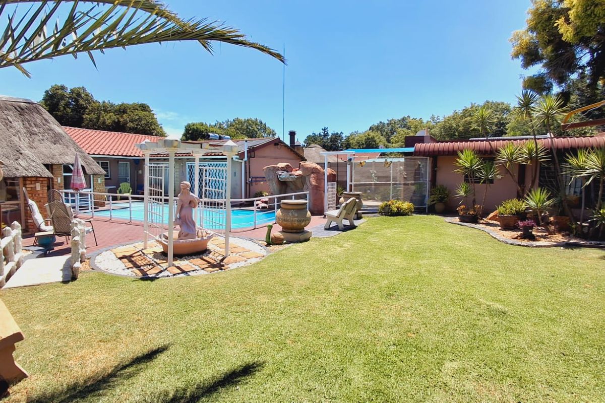 A spacious backyard featuring a swimming pool, paved patio area, and well-maintained lawn, providing an ideal space for outdoor relaxation and entertainment.