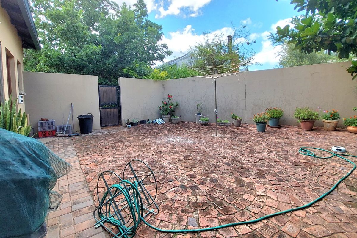 A private rear courtyard featuring circular brick paving, a boundary wall, and a rotary clothesline, offering a functional outdoor space.