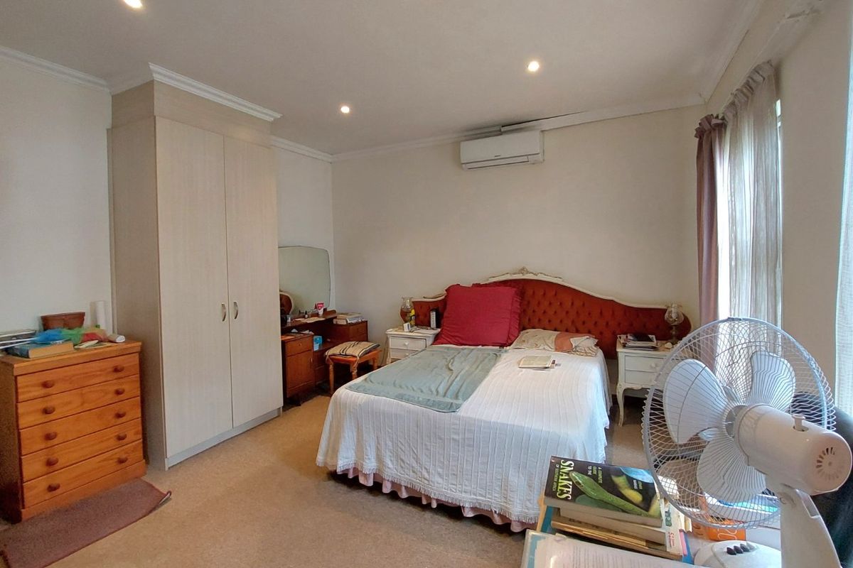 A functional bedroom featuring a built-in wardrobe, split-system air conditioning, and recessed downlighting.
