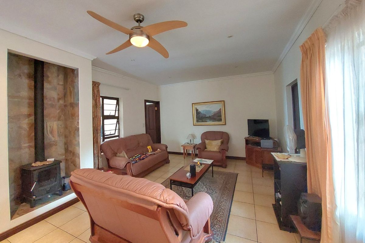 Spacious living room featuring tiled flooring, a stone-surround freestanding fireplace, and a ceiling fan, offering a comfortable and functional layout.