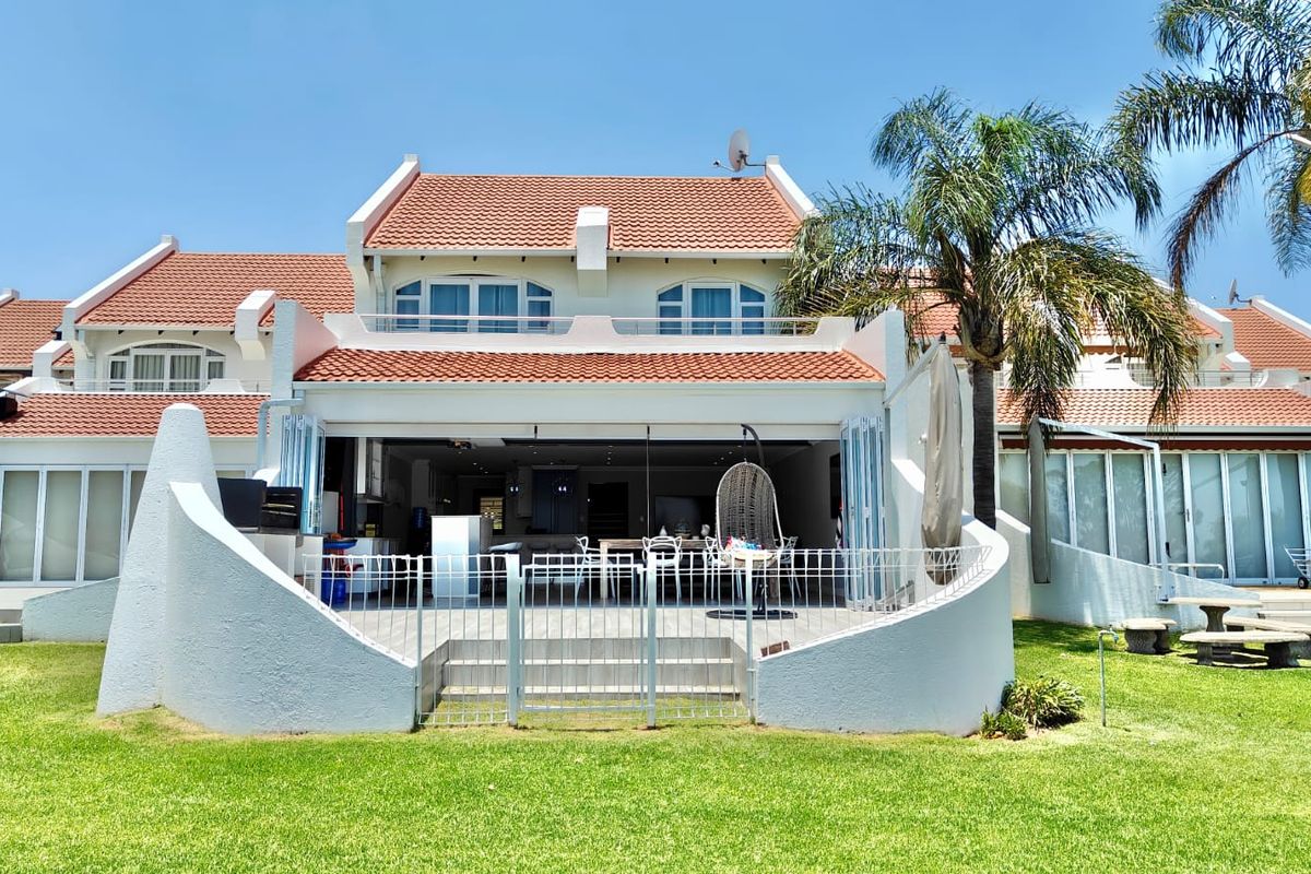 Rear view of the property featuring a paved patio area, bi-fold doors leading to the interior, and a well-maintained garden.