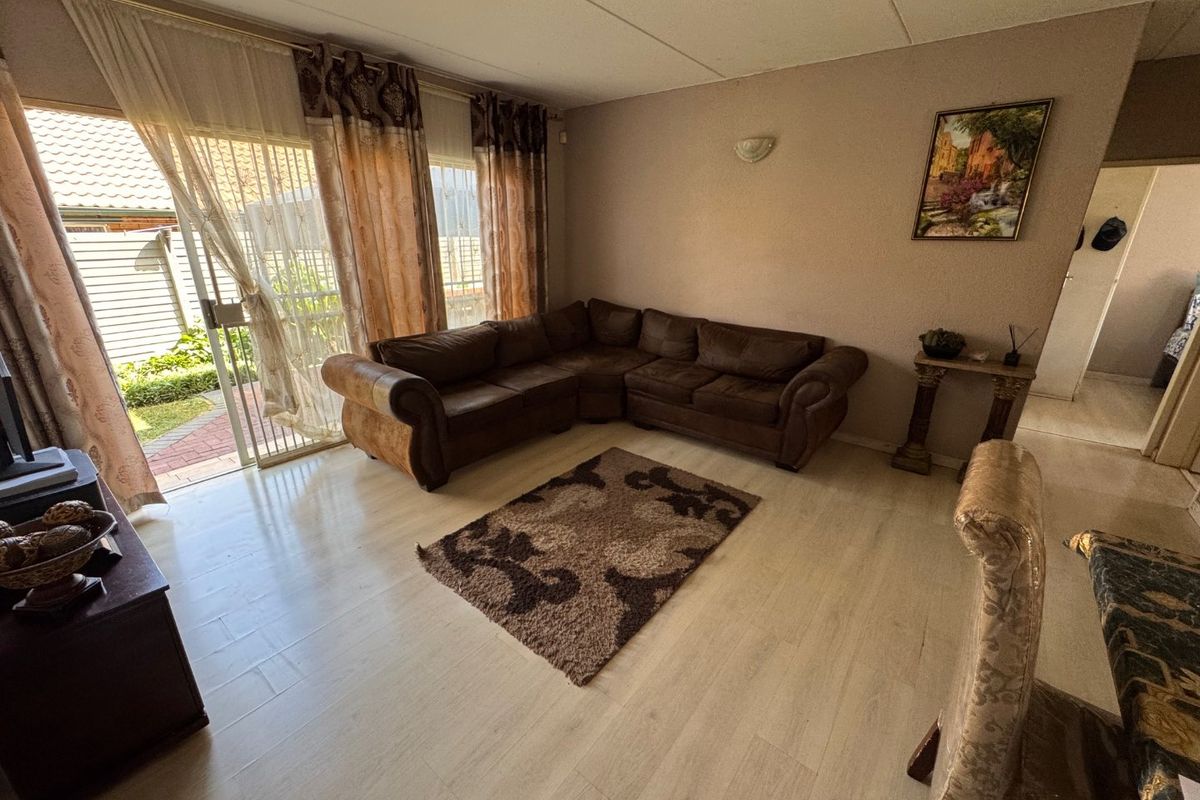 A living room featuring light-toned laminate flooring and large sliding glass doors that provide direct access to the outdoor patio area.