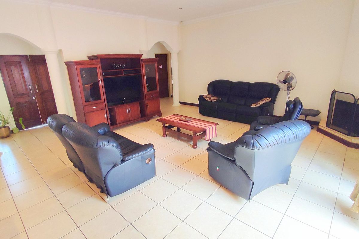 Spacious living room featuring tiled flooring, a fireplace, and architectural arched doorways, providing a comfortable and functional family gathering space.