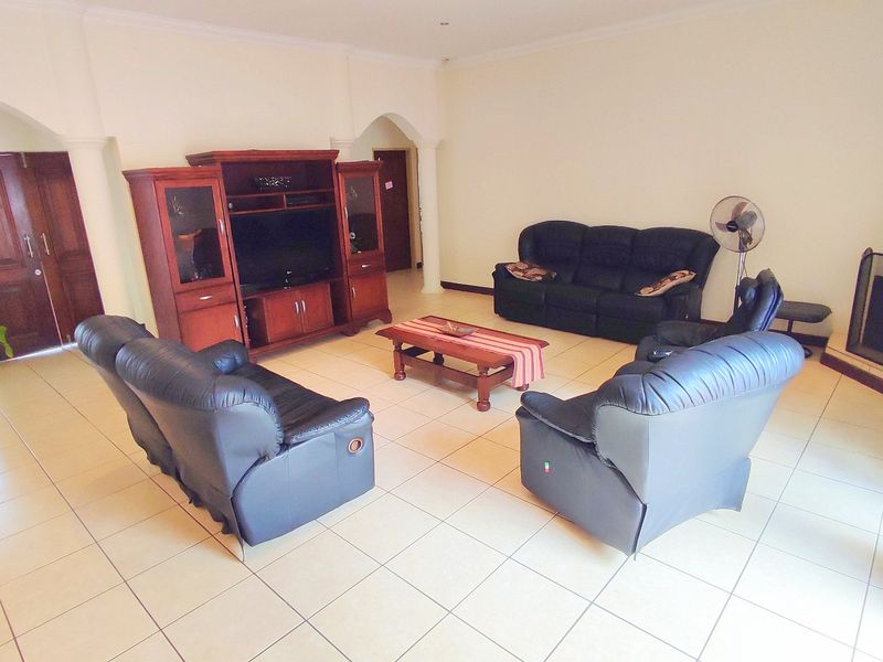 Spacious living room featuring tiled flooring, a fireplace, and architectural arched doorways, providing a comfortable and functional family gathering space.