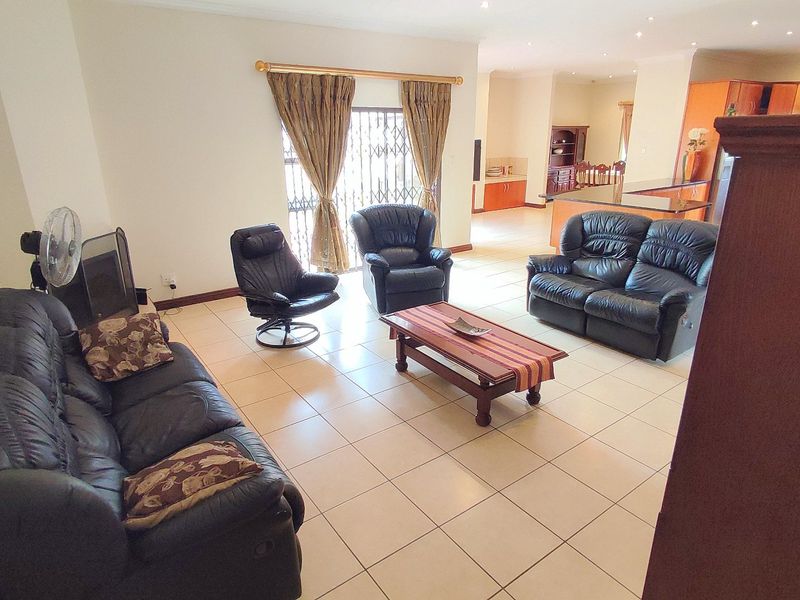Spacious open-plan living area featuring tiled flooring, recessed lighting, and a seamless flow into the adjacent kitchen space.