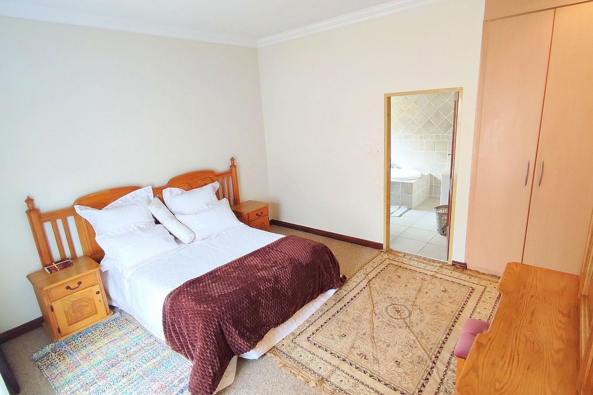 A carpeted bedroom featuring built-in cupboards and direct access to an en-suite bathroom.