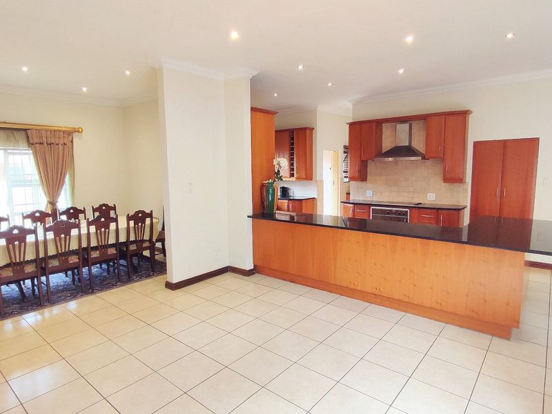 Open-plan kitchen and dining area featuring tiled floors, wooden cabinetry, granite countertops, and integrated appliances, offering a functional and spacious layout.