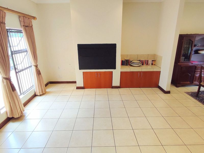 Spacious living area featuring tiled flooring, a central built-in fireplace, and integrated cabinetry, offering a functional layout for comfortable family living.