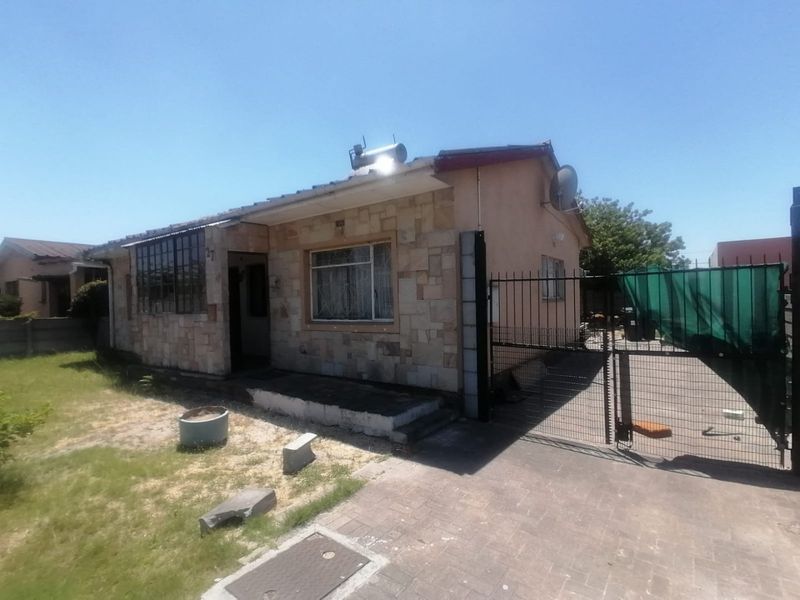 Front elevation of a single-story house featuring stone cladding, a solar geyser, paved driveway, and secure metal gate access.