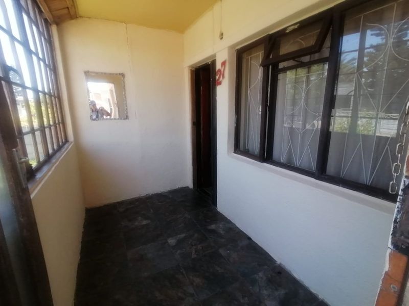 A covered entrance patio featuring tiled flooring and security window bars, providing a functional transition space to the main entrance.