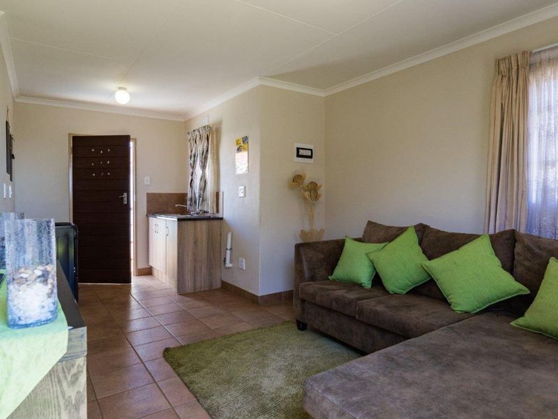 Open plan living area featuring tiled flooring and a compact kitchenette with built-in cabinetry and sink.