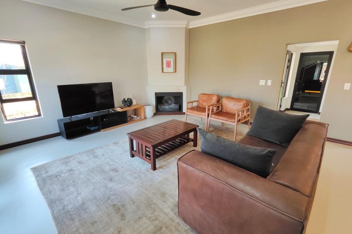 A comfortable living room featuring a corner fireplace, ceiling fan, and neutral wall tones, providing a functional and inviting space for relaxation.