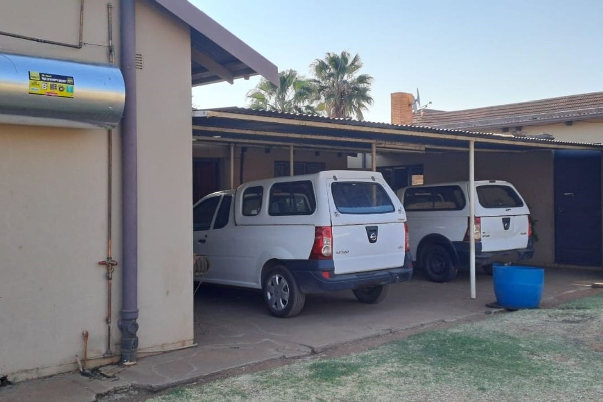 Rear exterior view showing a carport structure and an externally mounted geyser unit on the side wall.