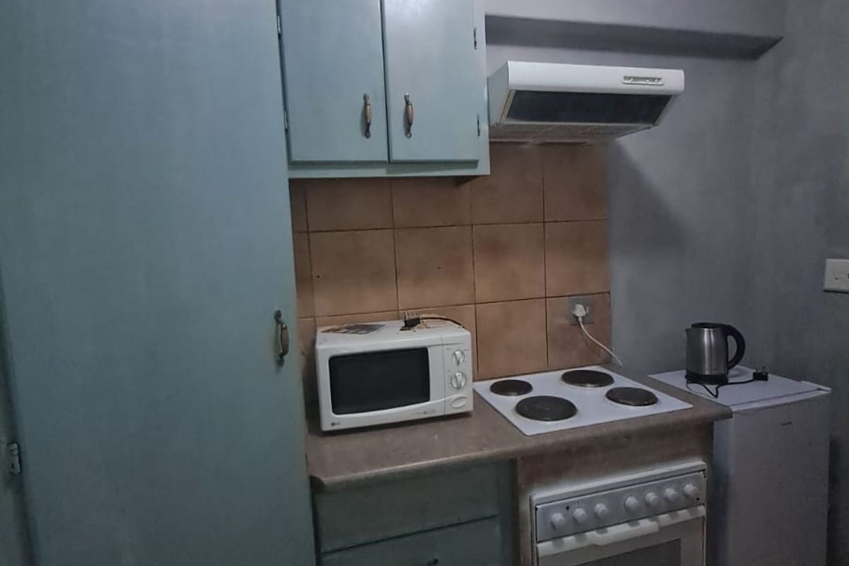 A compact kitchen featuring dated cabinetry, a tiled backsplash, and built-in cooking appliances, offering potential for a modern renovation.