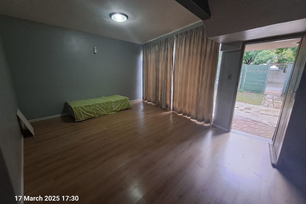 Spacious living area featuring laminate flooring and direct access to the rear garden through a sliding glass door.