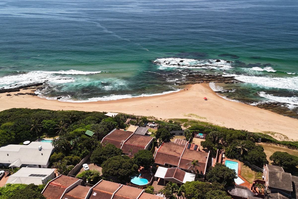 Aerial view of a coastal townhouse complex featuring swimming pools and direct proximity to the beach and ocean.