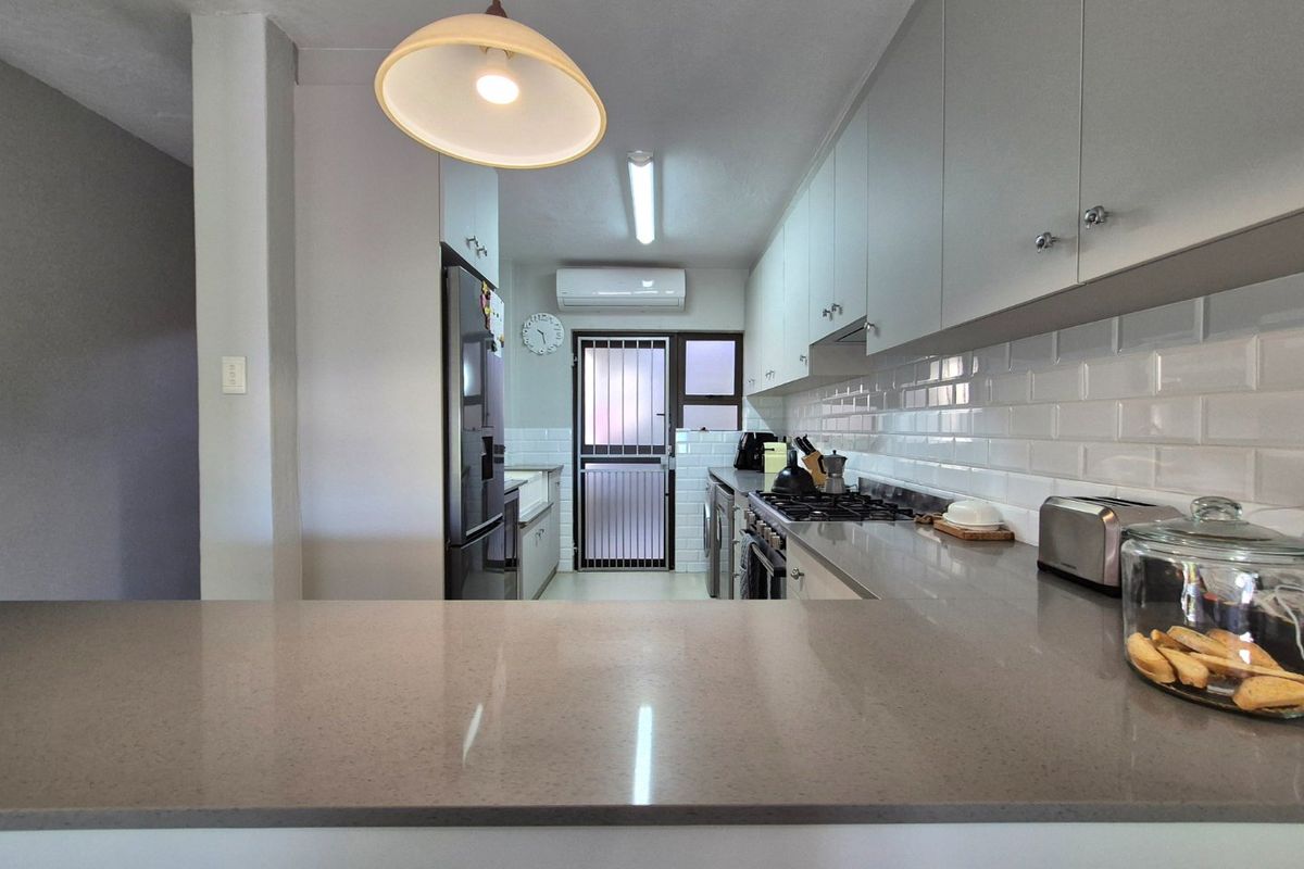 Modern kitchen featuring quartz countertops, subway tile backsplash, gas hob, built-in oven, and a split-system air conditioner for climate control.
