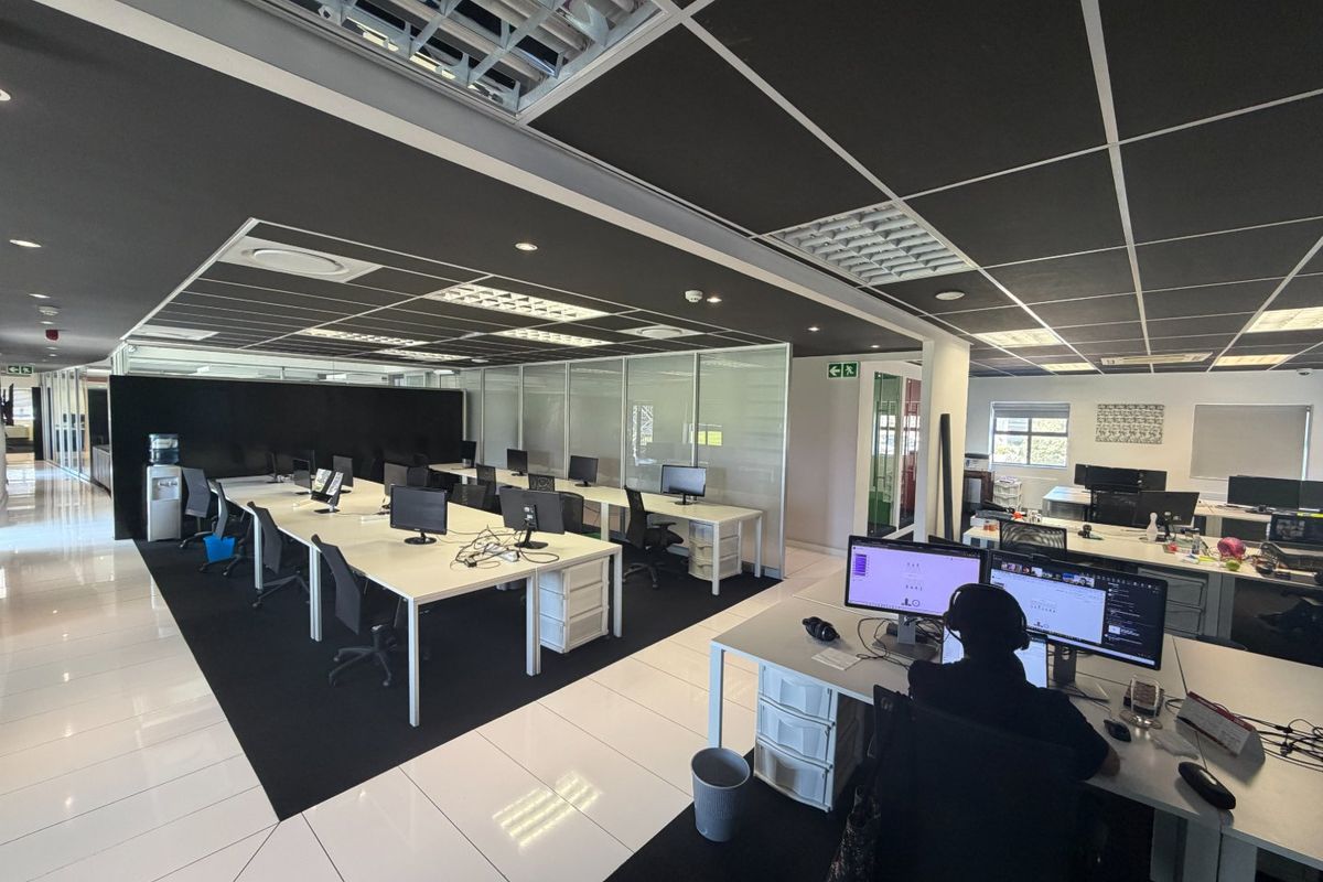 Modern open-plan commercial office space featuring suspended acoustic ceiling tiles, recessed lighting, glass partitioning, and polished tiled flooring.