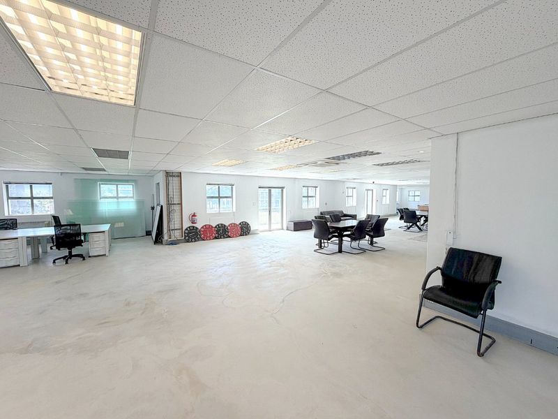 Spacious open-plan commercial office area featuring a suspended ceiling, recessed lighting, and durable concrete flooring, suitable for a flexible workspace layout.