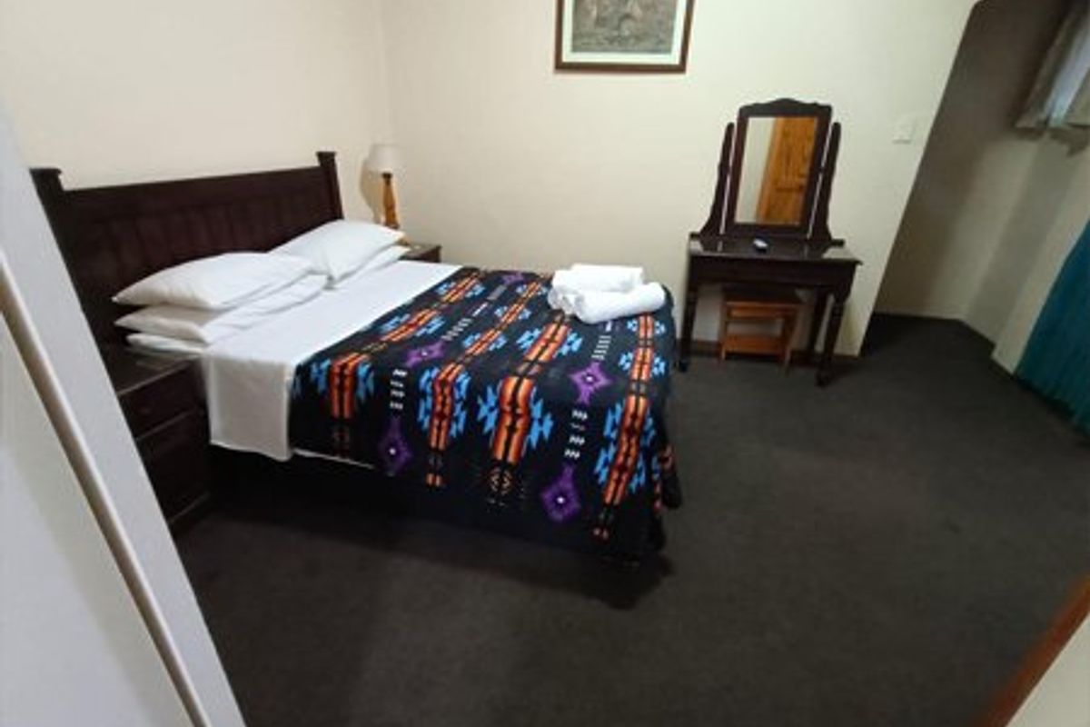 A functional bedroom featuring dark carpeting and an arched entryway, providing a simple and comfortable sleeping space.