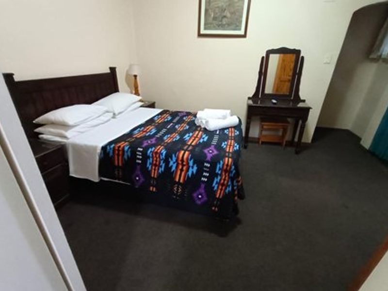 A functional bedroom featuring dark carpeting and an arched entryway, providing a simple and comfortable sleeping space.
