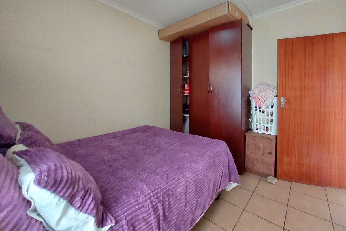 A functional bedroom featuring tiled flooring, a built-in wardrobe, and coved ceiling details.
