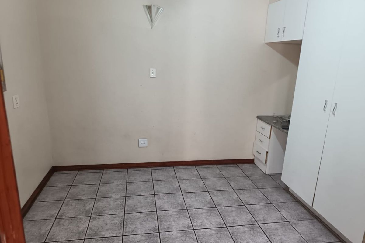 An empty bedroom featuring tiled flooring, built-in cupboards, and wall-mounted lighting, providing a blank canvas for personalization.