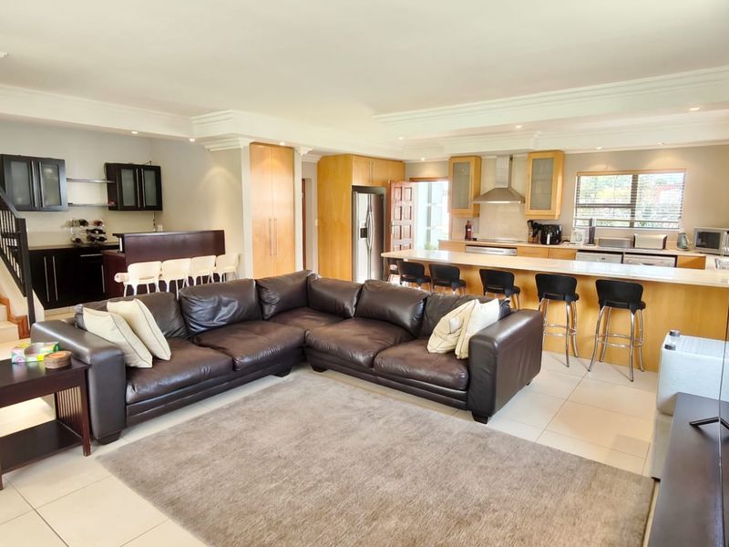 Spacious open-plan living area featuring a modern kitchen with a large island, tiled flooring, and a staircase leading to the upper level.