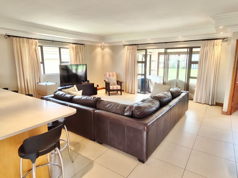 Spacious open-plan living area featuring a kitchen island, tiled flooring, recessed lighting, and sliding glass doors leading to the outdoor space.