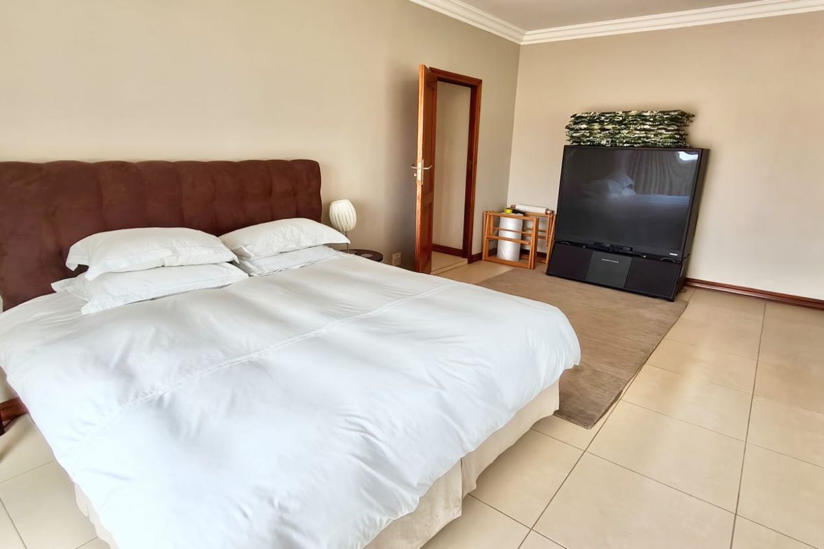 Spacious bedroom featuring neutral wall tones, tiled flooring, and classic cove cornicing, offering a clean and functional living space.