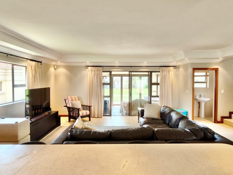 Spacious open-plan living area featuring tiled floors, recessed lighting, and direct access to the patio through large sliding glass doors.
