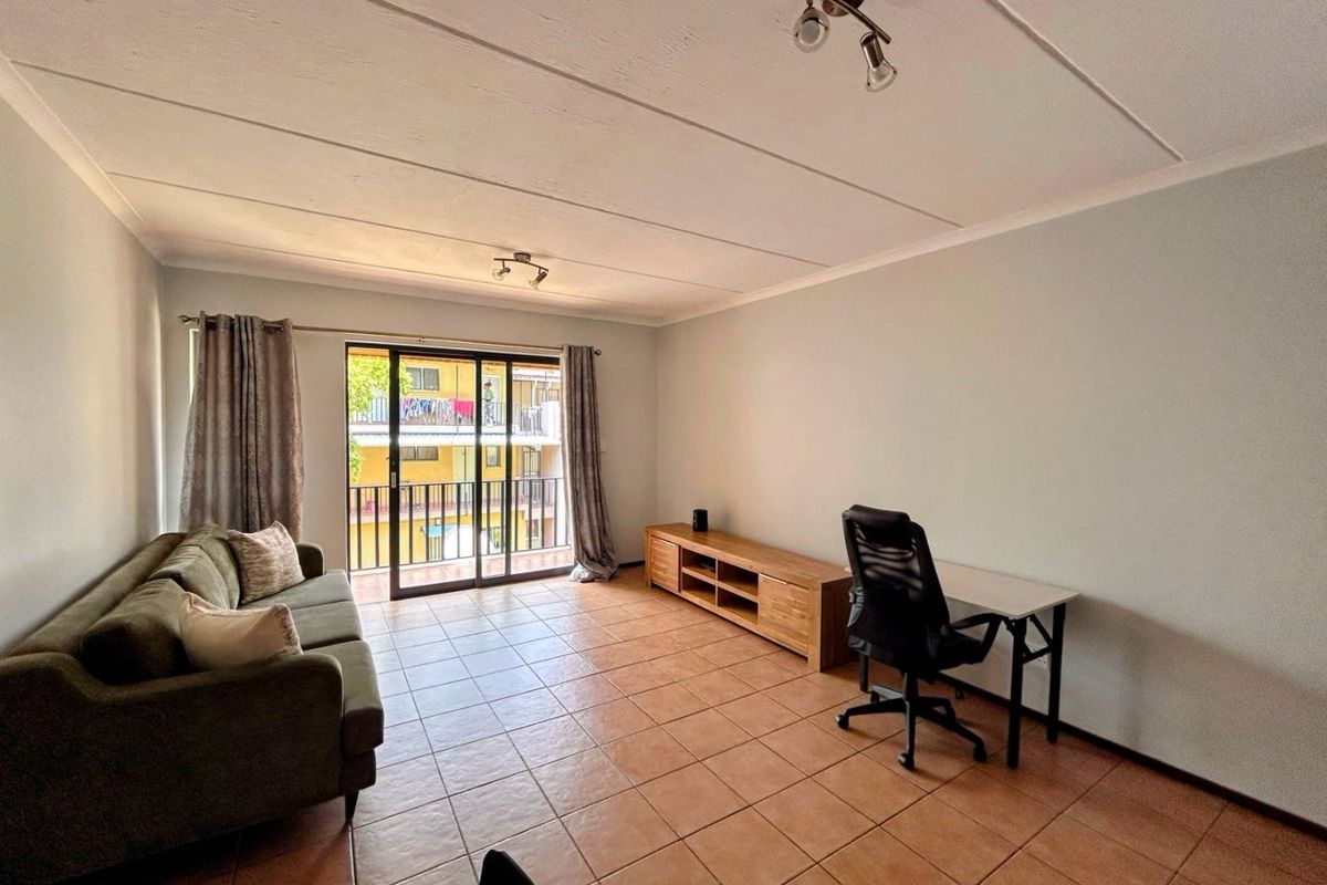 Spacious living room featuring tiled flooring, coved ceilings, and a sliding glass door providing access to a balcony.