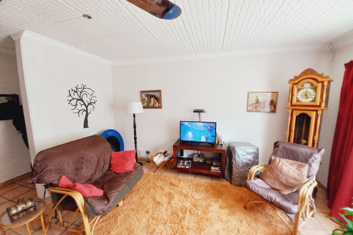 A living room featuring tiled flooring and a textured ceiling, providing a functional space for relaxation.