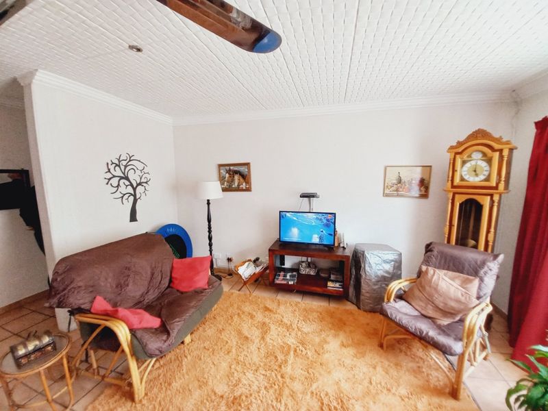 A living room featuring tiled flooring and a textured ceiling, providing a functional space for relaxation.