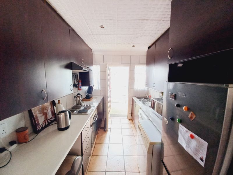Galley-style kitchen featuring dark cabinetry, tiled flooring, and direct access to an outdoor area.