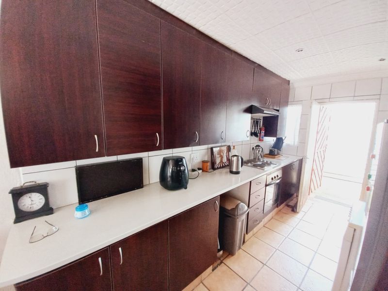 A functional kitchen featuring dark wood-finish cabinetry, white countertops, tiled flooring, and a built-in oven with an extractor fan.