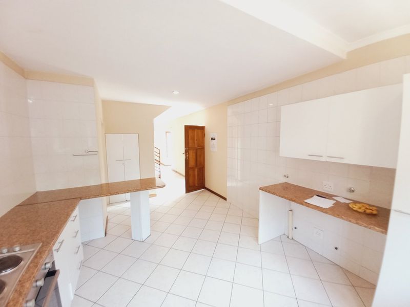 A functional kitchen featuring white cabinetry, laminate countertops, tiled splashbacks, and ceramic flooring, offering a clean and neutral space ready for personalization.