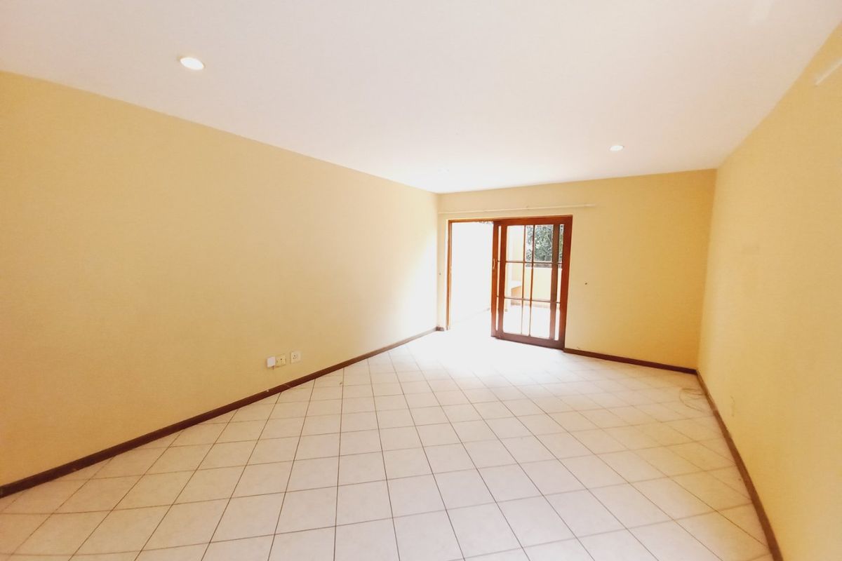 A spacious, empty living area featuring neutral walls, tiled flooring, recessed lighting, and a sliding glass door providing access to the outdoors.