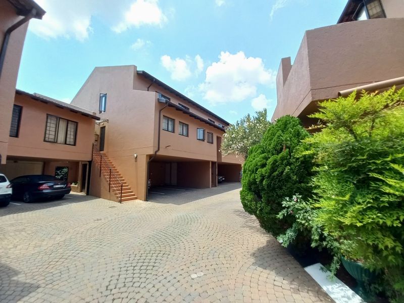 Exterior view of the apartment complex featuring a paved driveway, covered parking bays, and external staircase access to upper units.