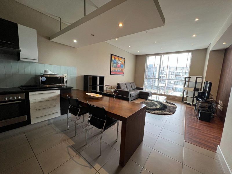 Modern open-plan apartment featuring a sleek kitchen with built-in cabinetry, tiled floors, and expansive windows providing ample natural light to the living area.