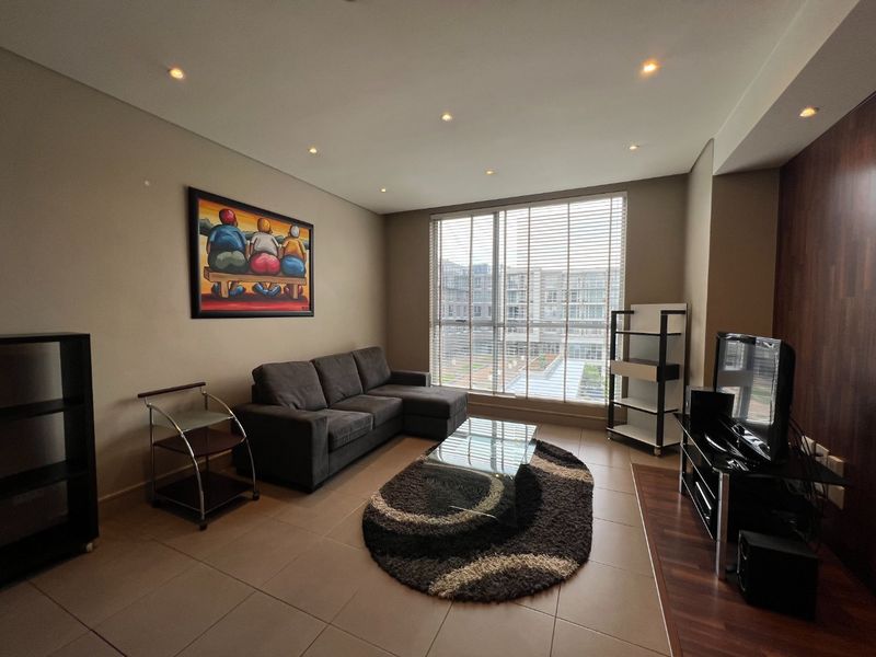A well-maintained living room featuring tiled floors, recessed lighting, and a wood-look feature wall, with large windows providing ample natural light.