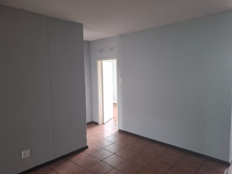 An empty hallway featuring tiled flooring and neutral wall finishes, providing access to adjacent rooms within the apartment.
