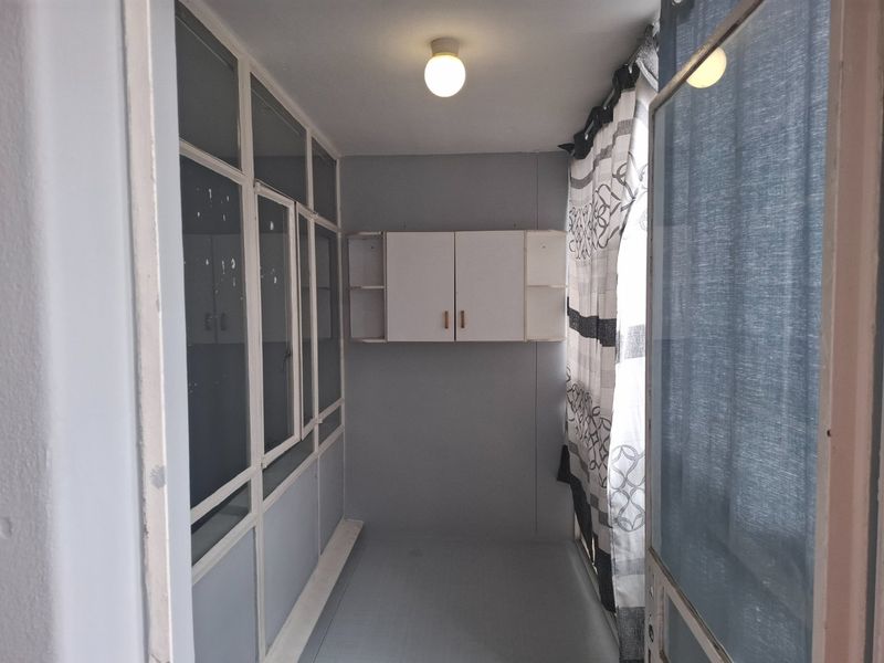 An enclosed balcony or sunroom featuring built-in wall cabinetry, glass partitions, and neutral finishes, offering a versatile additional living space.