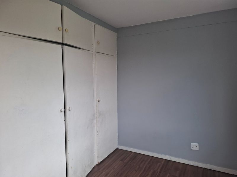 A vacant bedroom featuring laminate flooring and built-in cupboards with a neutral grey wall finish.