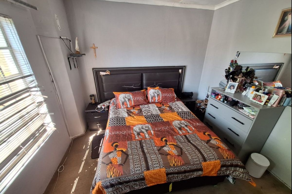 A bedroom featuring a window with venetian blinds and coving, requiring cosmetic updates to the flooring and wall finishes.