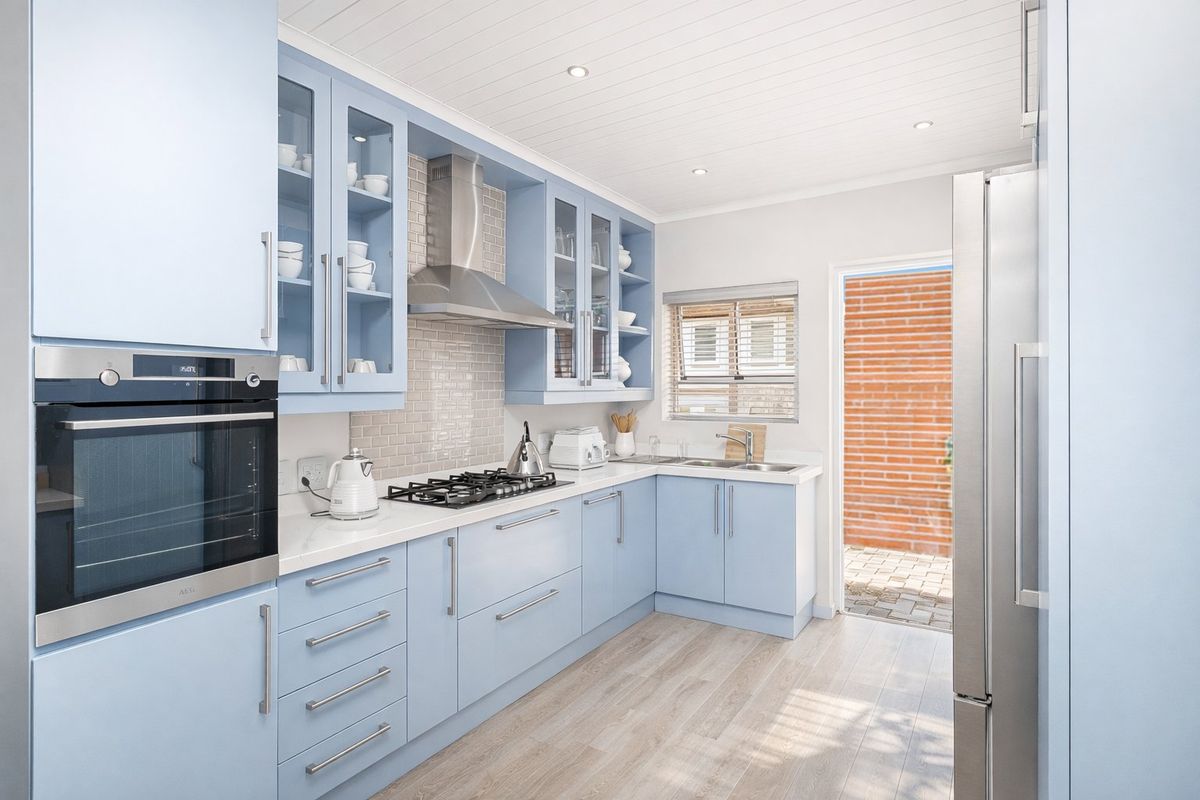 Modern kitchen featuring light blue shaker-style cabinetry, subway tile backsplash, built-in oven, gas hob, and direct access to an outdoor area.