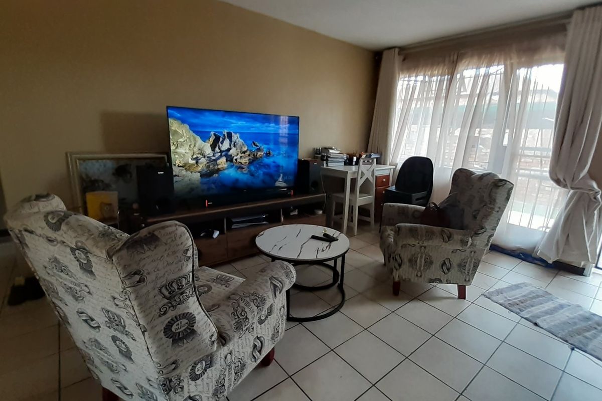 A living room area featuring tiled flooring and a sliding glass door providing access to the exterior.