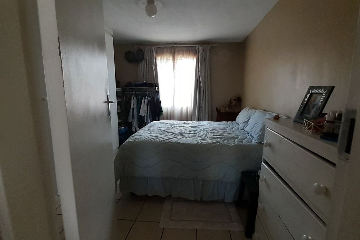 A compact bedroom featuring tiled flooring and a built-in cupboard, requiring cosmetic updates to improve its overall appeal.