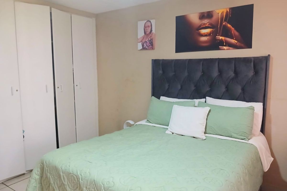 A bedroom featuring built-in cupboards with white doors and tiled flooring.