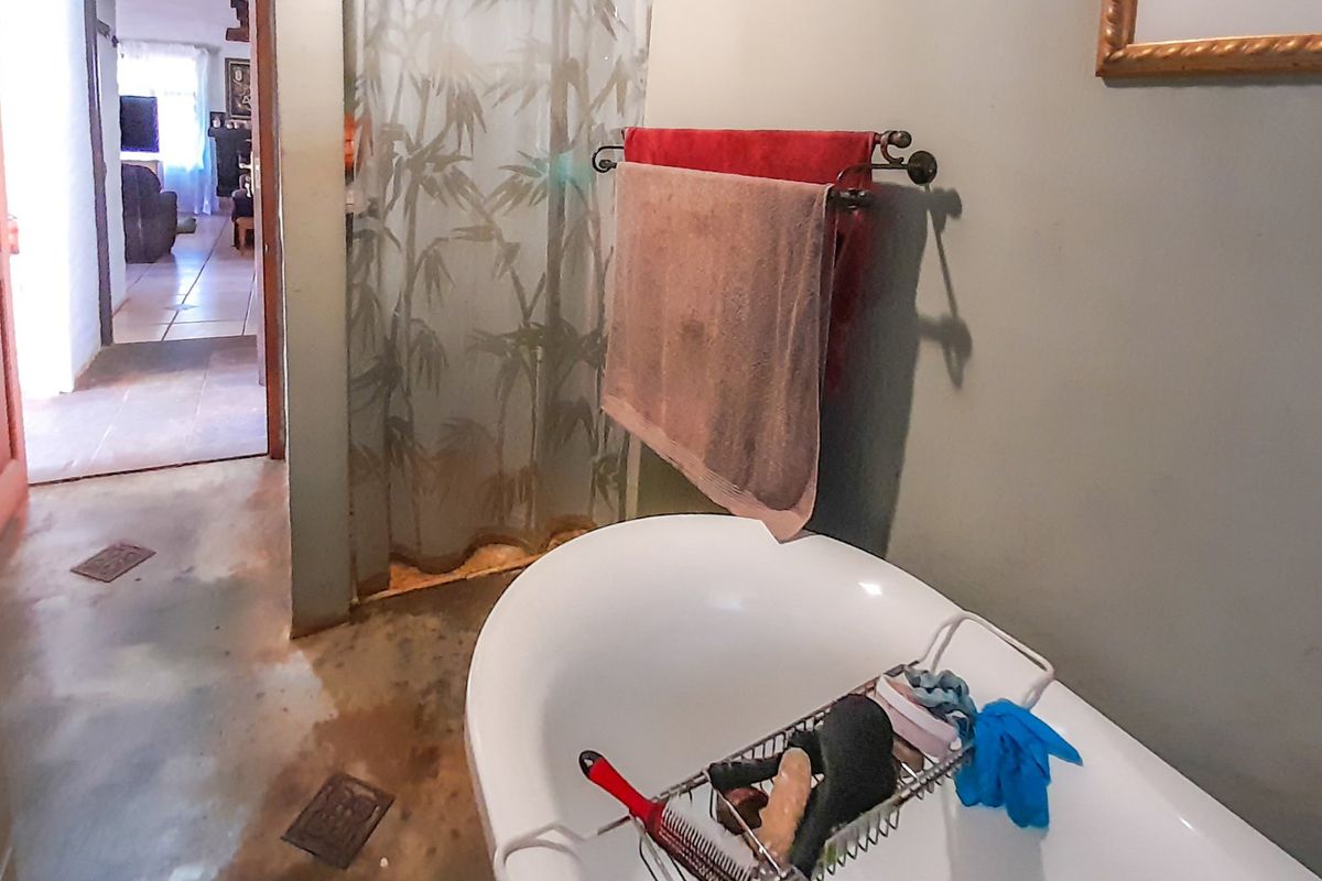 A bathroom featuring a freestanding bathtub and shower area with visible wear on the flooring.